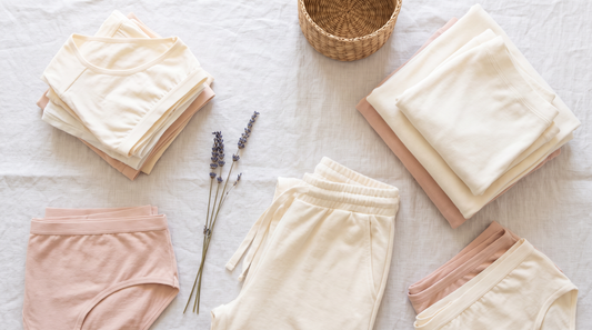 Folded cream and blush cotton underwear and lounge garments arranged on pale linen with lavender