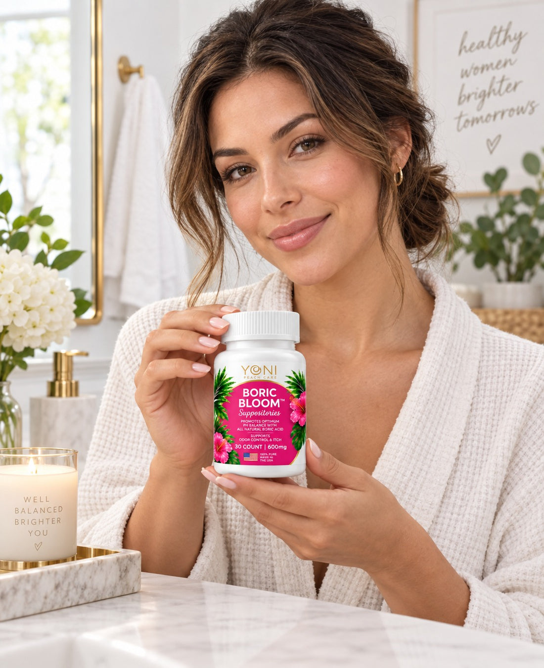 Woman in a white robe holding Boric Bloom suppositories at a bathroom vanity