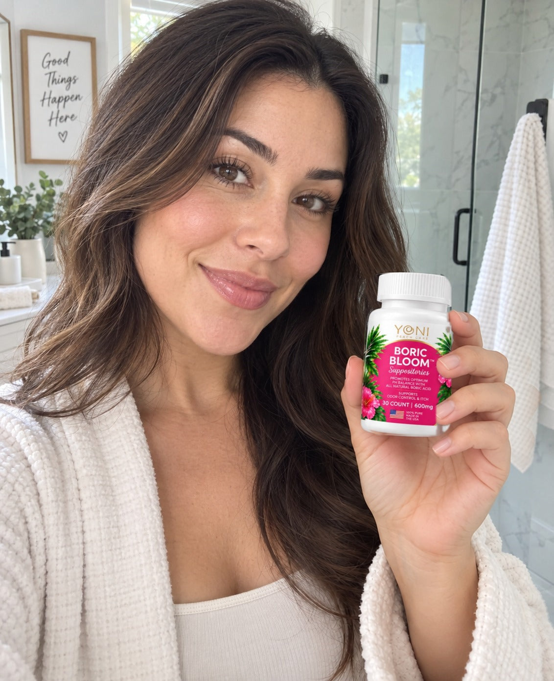 Woman with long dark hair holding a Boric Bloom suppositories bottle in a bright bathroom